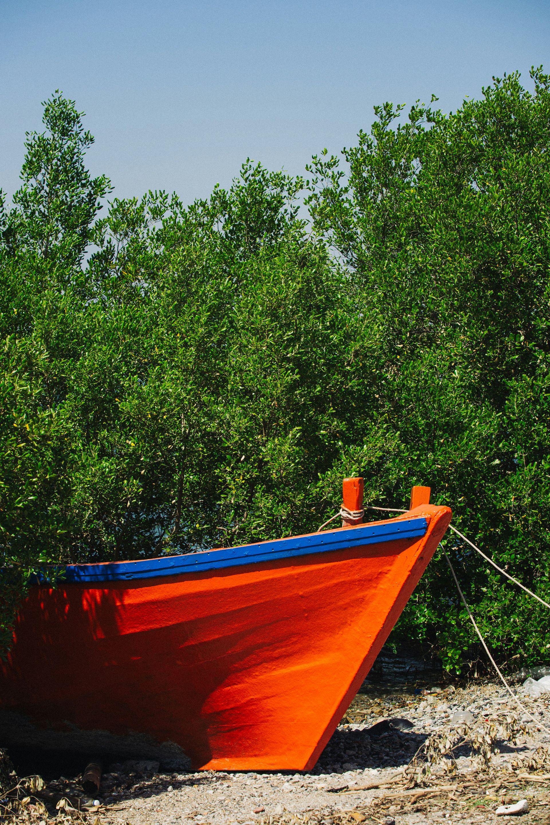 An orange boat rests near green trees